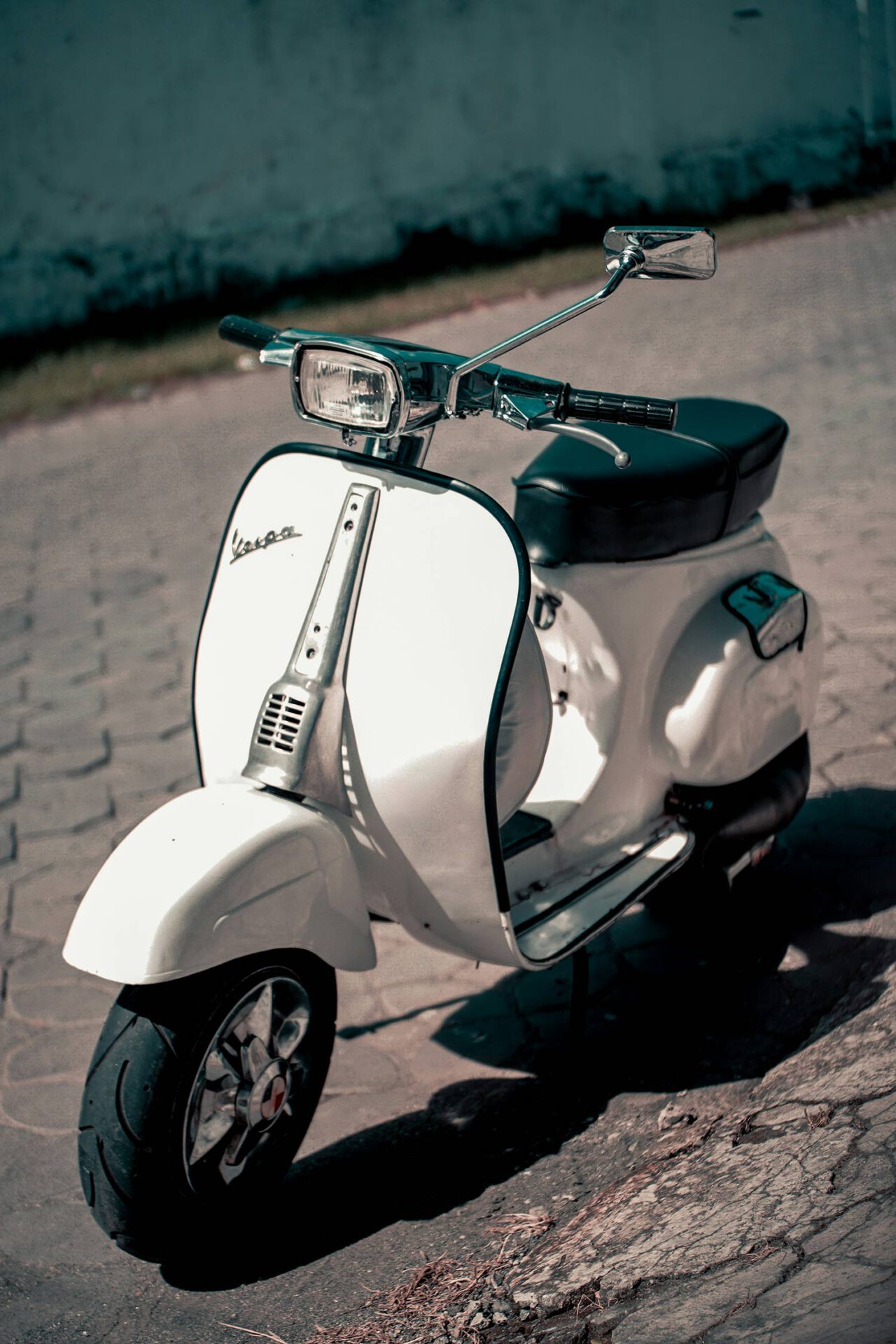 Een vintage witte Vespa-scooter geparkeerd op een straat met een licht vervaagde achtergrond.